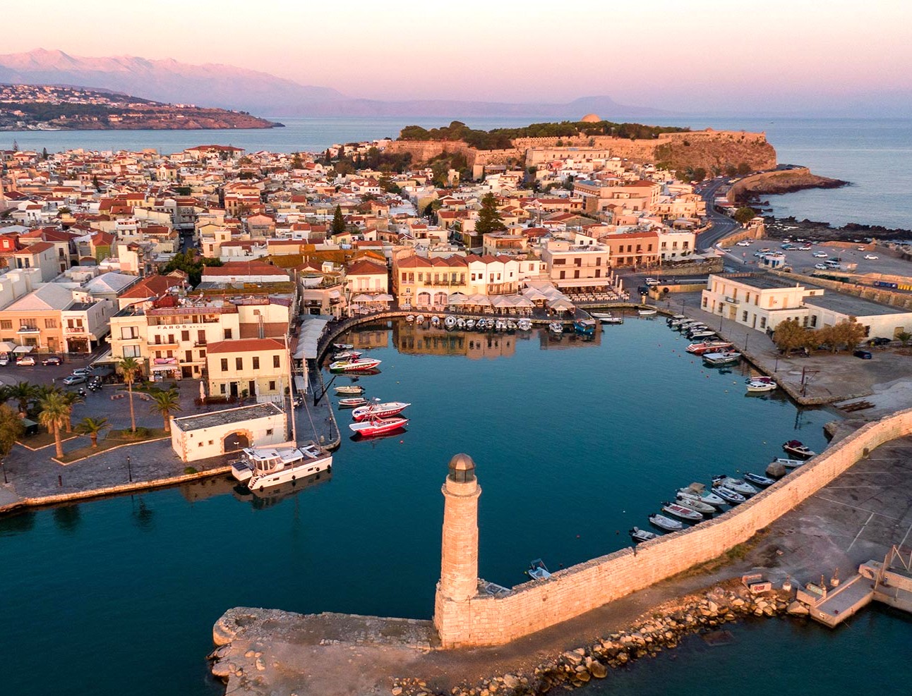 Rethymno port with a lighthouse and moored boats, overlooking the town and Venetian Fortezza Castle.